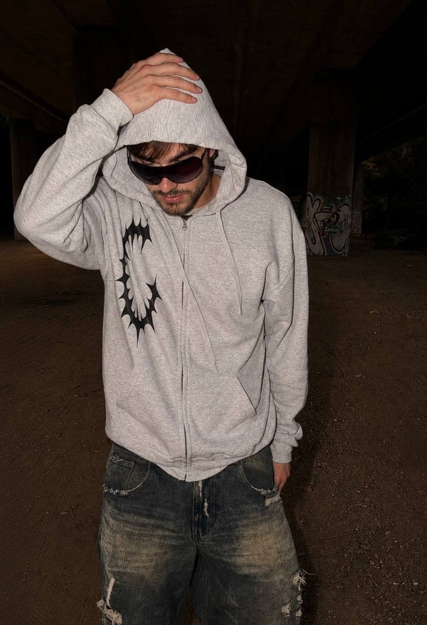 German Wasteland Sigil Zip-Up Hoodie styled product photo with grey zip hoodie, black sigil graphic and oversized denim streetwear fit